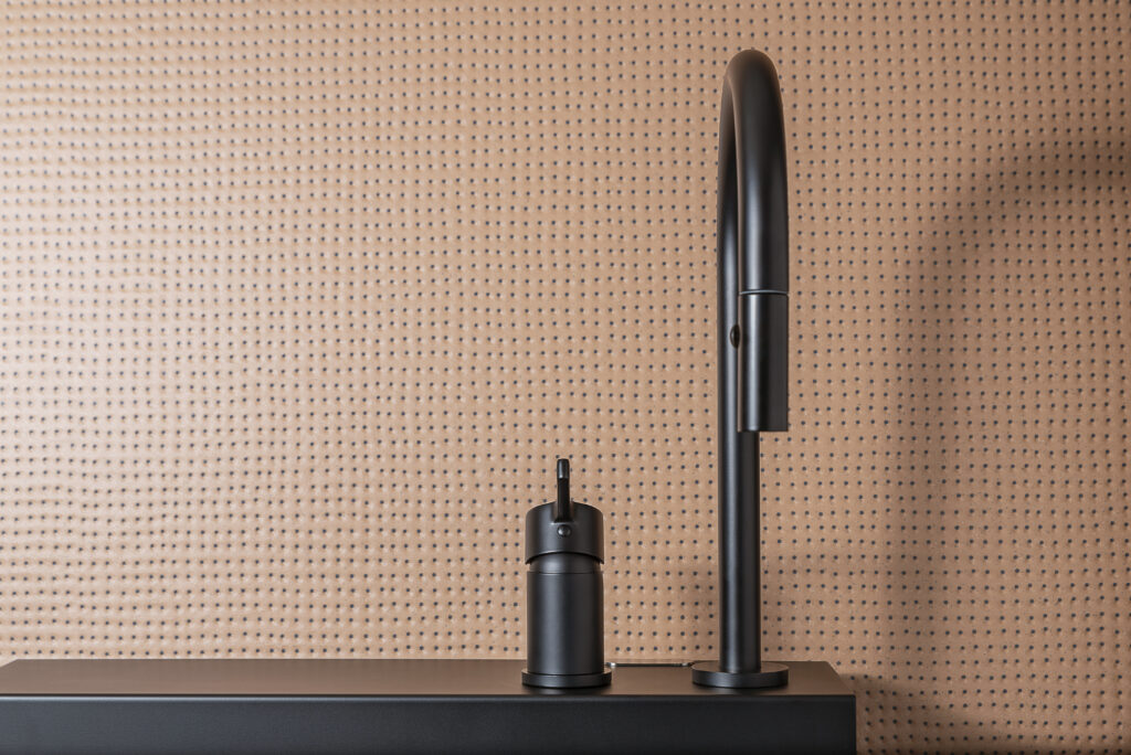 Matte black Cropelli mixer on dark surface with pegboard wall