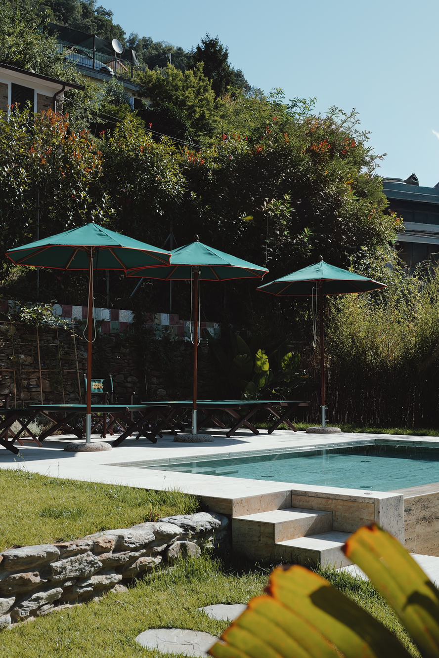 Piscina con ombrelloni nel giardino di Dimora Moncher